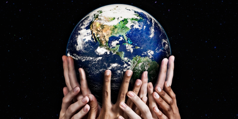 A group of hands hold up a globe