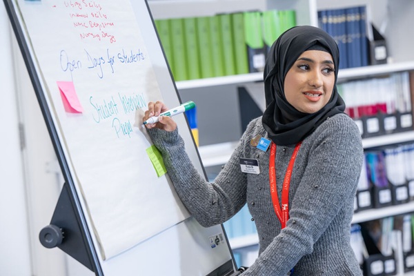 A student writing on a flipchart and speaking to an audience