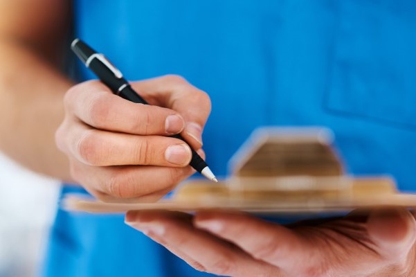 close-up of nursing staff member signing document on clipboard