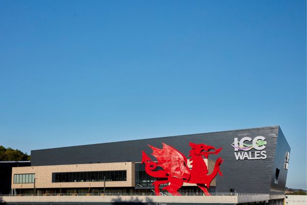 The International Convention Centre in Wales under a blue sky behind a red dragon statue