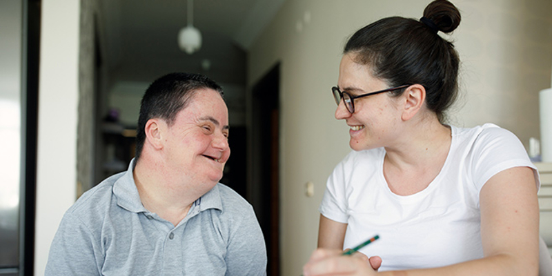 A man and a caregiver sitting at a table