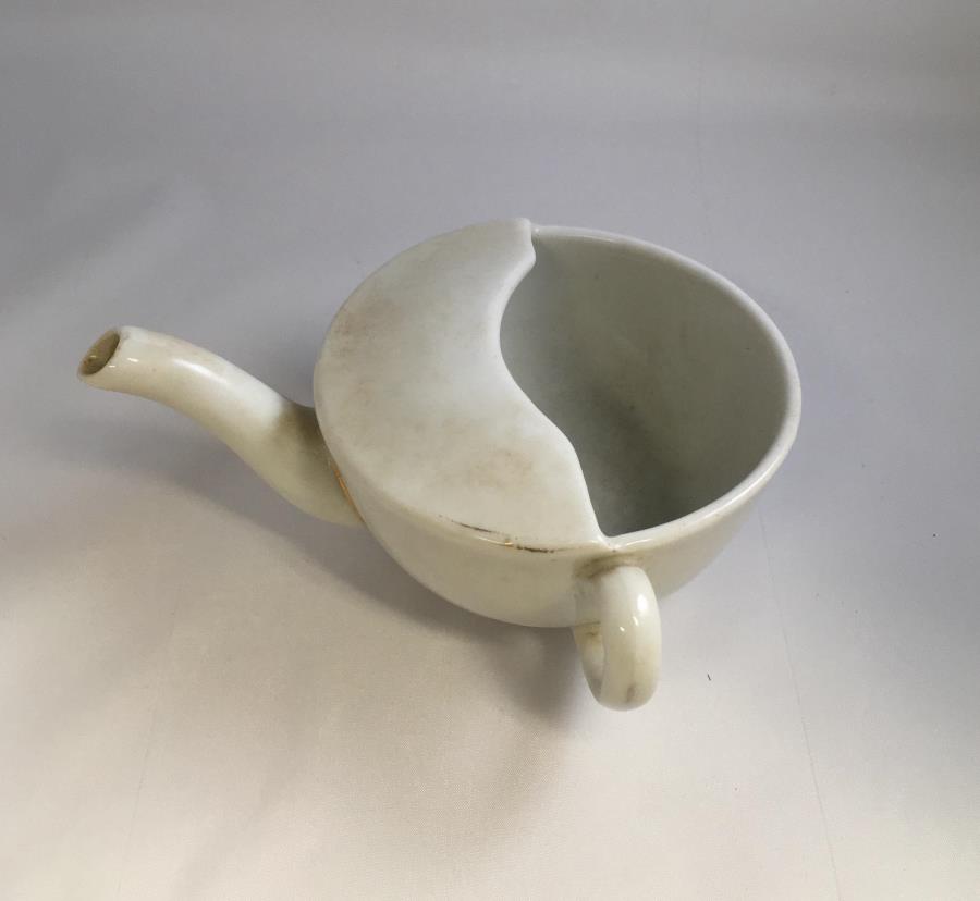 A white ceramic feeding cup c.1914 - 1918 with a spout like a teapot and a handle to the side.