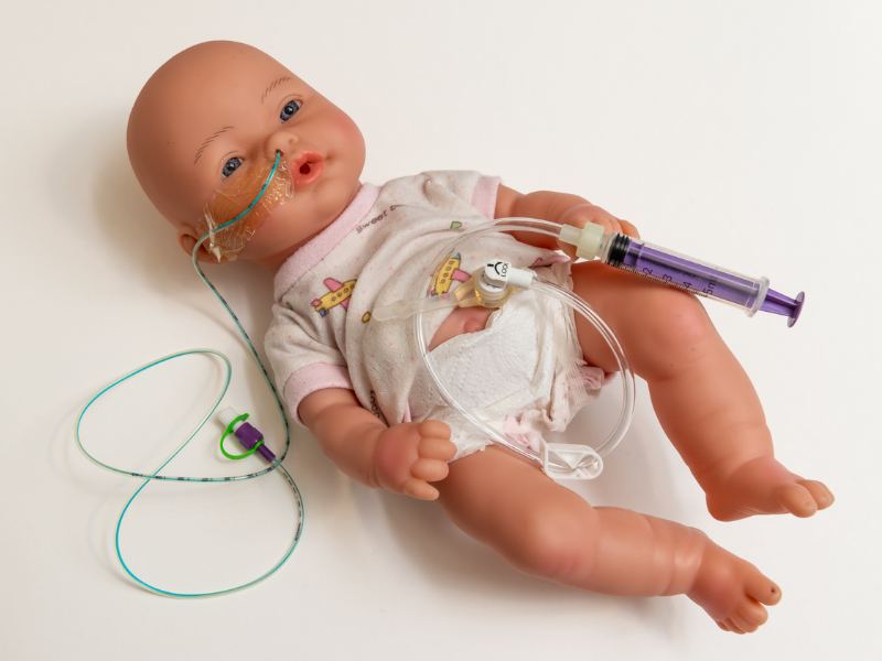 photo of a baby doll with tubes attached to its face and body