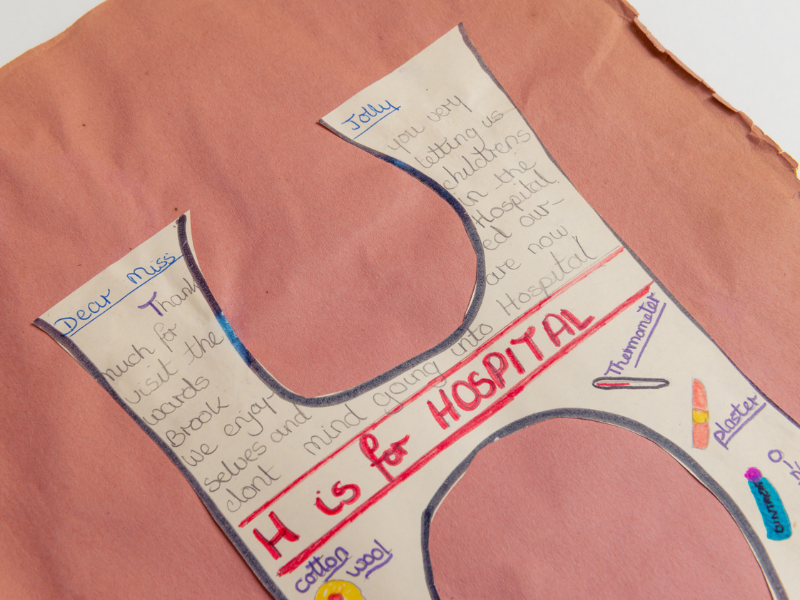 close up of a cut out letter 'H' with children's writing saying 'H is for HOSPITAL'