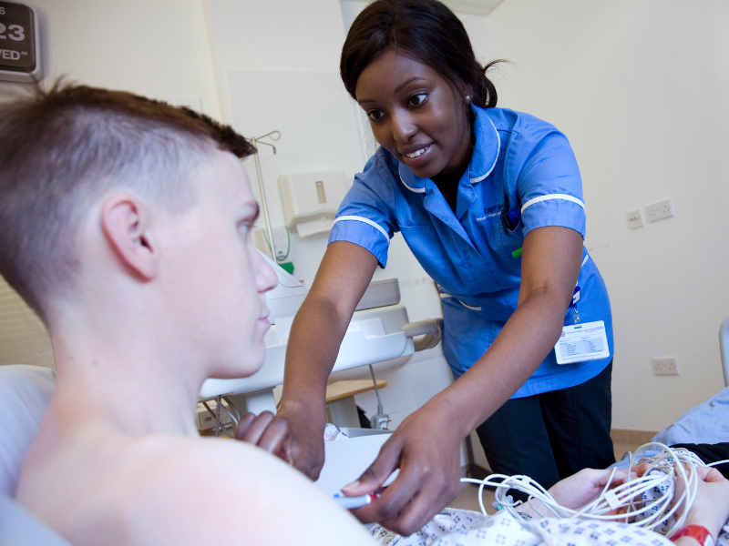 photo of nurse assisting a teenage male patient
