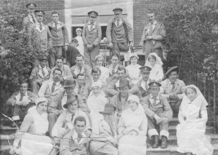 Black and white image of a group nurses wounded soldiers sitting on a flight of stairs. 