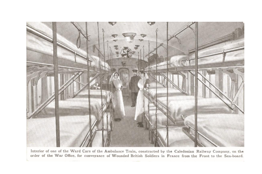 Black and white image with 2 nurses and a man in uniform standing between 2 rows of beds on either side of a carriage. 