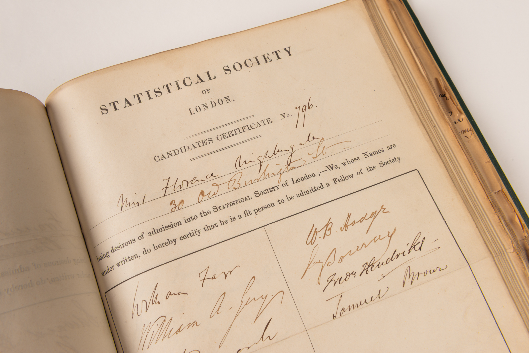 Close up of an open book showing a page titled Statistical Society off London Candidate's Certificate No. 79. Below are the handwritten names of Florence Nightingale and her various signatories.