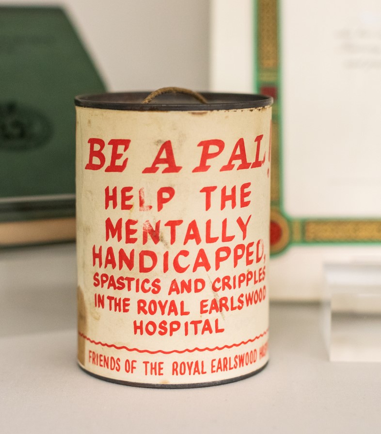 A white collection tin with red writing. 