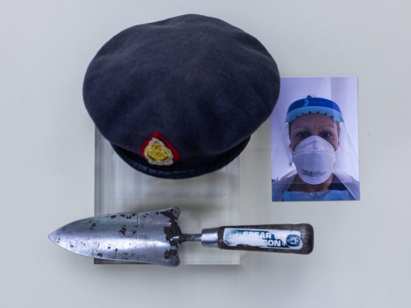 photograph of a nurse in PPE, gardening trowel, army beret