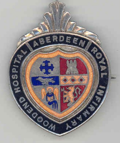 Teardrop shaped silver badge, with black banner on the outside saying Aberdeen Royal Infirmary Woodend Hospital centred around a coat of arms