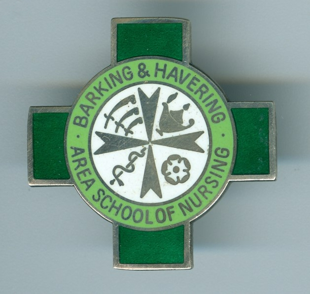 An enamelled badge with a white centre featuring a cross and other symbols, surrounded by a light green circular banner containing the name of the school backed by a dark green cross. 