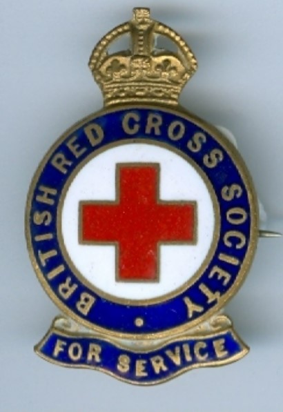A gold and enamel badge featuring a red cross in the centre, with a white background. Surrounded by a dark blue circular banner saying 'British Red Cross Society For Service'. This is surmounted by a gold crown. 