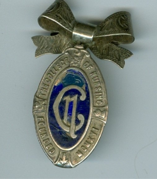 Blue and gold College of nursing badge, with metal bow fastening at the top. The badge is a lozenge shape, with the letters 'C' and 'N' in gold intertwined on a blue background