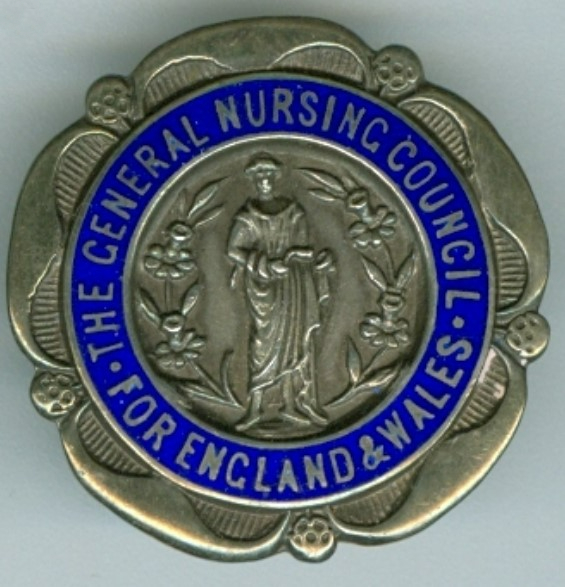 A round, silver badge, with five petal-like protrusions around the outside edge. There is a person surrounded by daffodils in the centre. Around the person is a blue banner saying general nursing council for England and Wales