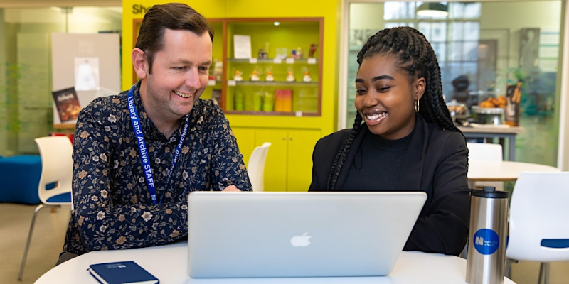 Two people sitting at a a laptop computer