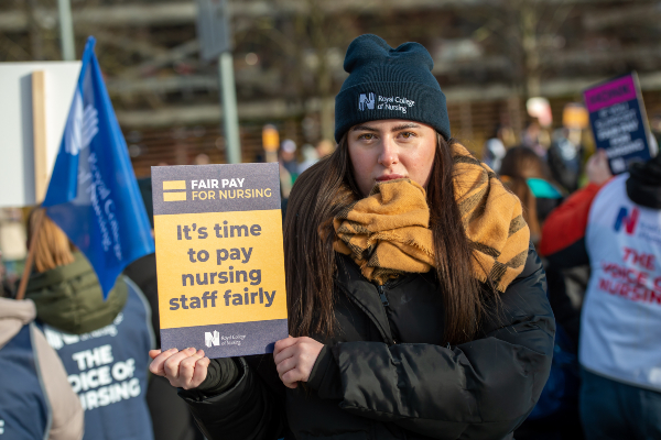Image of nurse standing on picket line holding placard