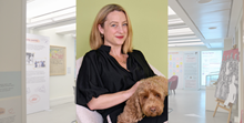 Christie Watson, a white woman in a black blouse, smiling, sits with a small brown dog on her lap against a yellow pastel background. Another more transparent image is pasted behind the one of Romalyn, showing an exhibition space with informational panels and artwork.