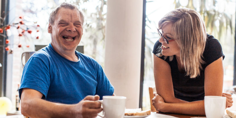 Man with learning disability laughing with carer
