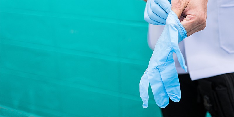 Health care professional putting on gloves