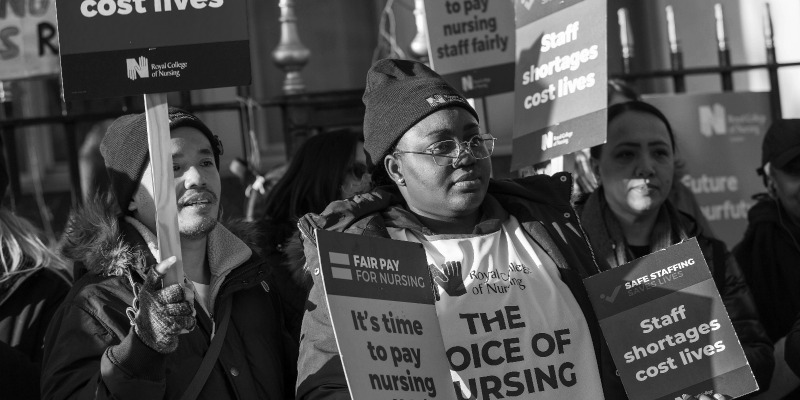 Black and white image of RCN members on strike holding 'safe staffing' placards