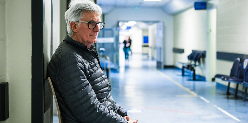 man sitting in empty hospital corridor