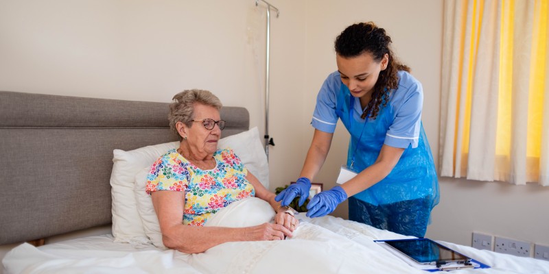 Social care worker attending to a woman in bed