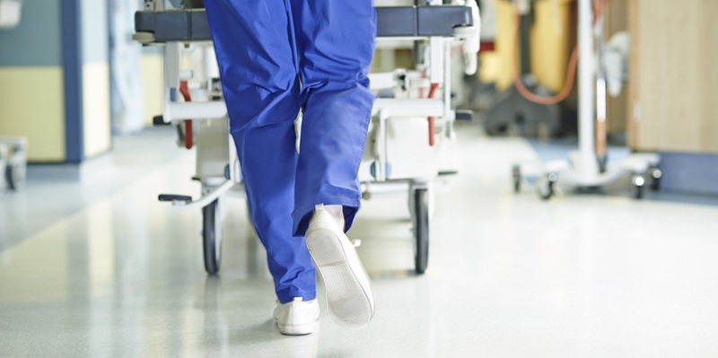 Medic running in scrubs down hospital corridor with gurney