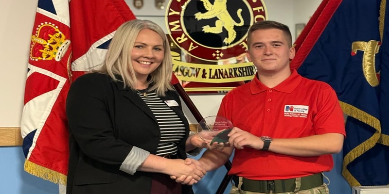 A woman handing a trophy to a young man in a King's Nursing Cadet uniform