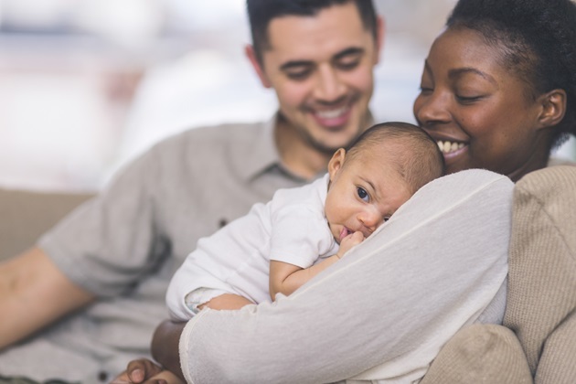 A new mum holds her baby and the father sits next to her