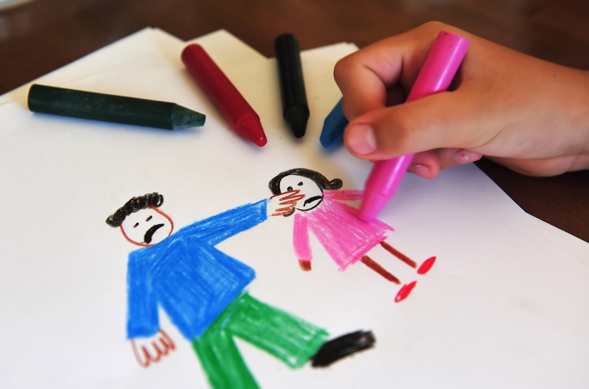 Child drawing a picture of an adult and child