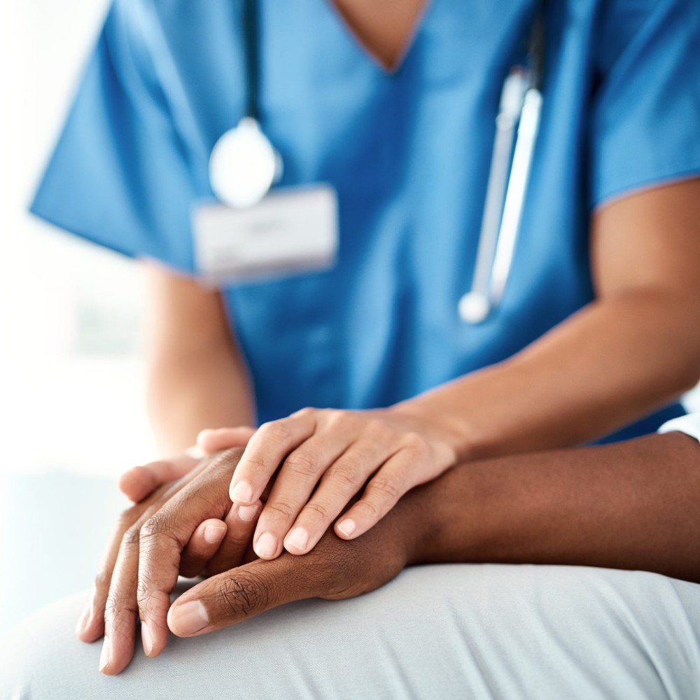 A nurse holds a patient's hand