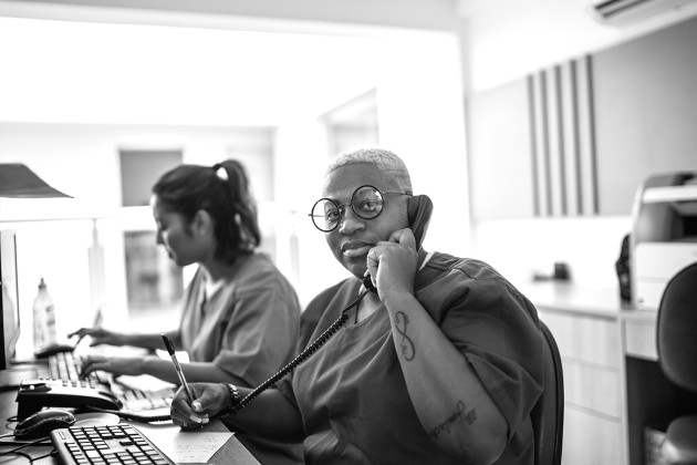 Black nurse with glasses on phone looking at camera