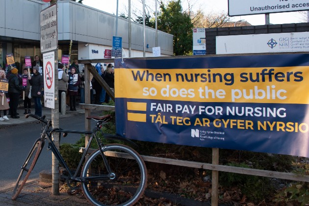 Strikers at picket line at University Hospital Wales, Cardiff on 15 December 2022. Banner shares message about patient safety