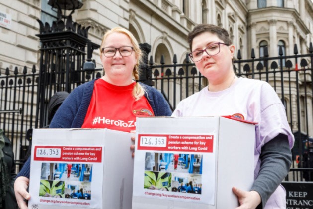 Rachel Hext and Cass Macdonald holding their long COVID compensation petition at the entrance to Downing Street