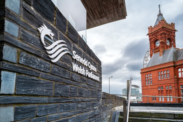 Sign for the Senedd Cymru / Welsh Parliament on the side of the building with the Cardiff Bay Pierhead building in the background