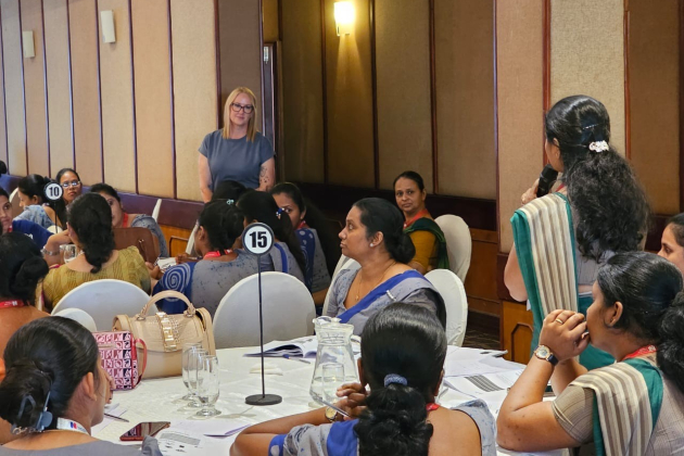 A Sri Lanka public health nurse speaks into a microphone to a group of colleagues 