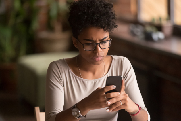 A woman reads her mobile phone and looks worried