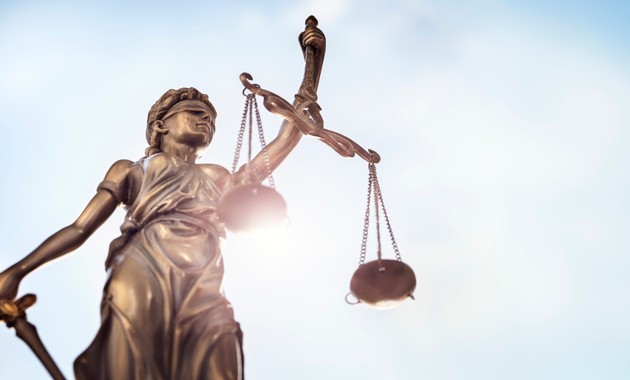 Lady Justice statue holding scales against blue sky