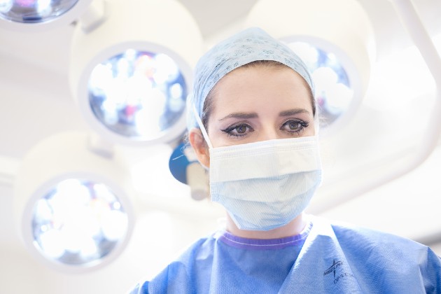 Surgical nurse Sara Dalby dressed in scrubs with theatre lights above her