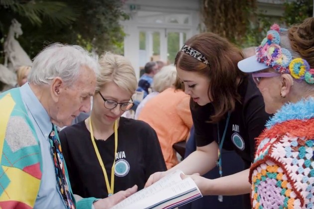 Two nursing students speak to two older people dressed in brightly coloured clothing