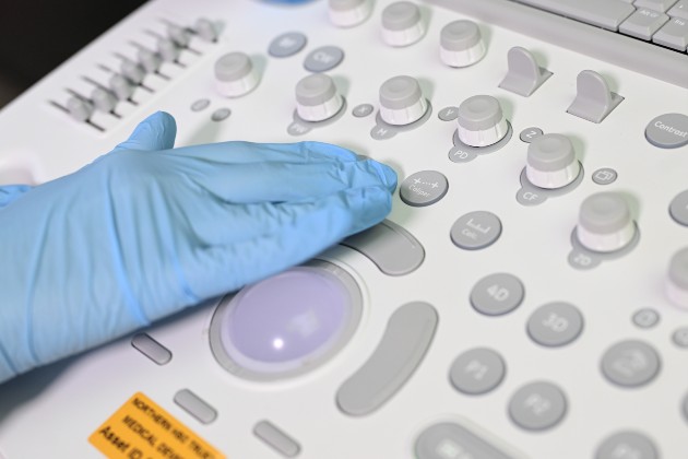 Hand clad in blue rubber glove operates scan buttons