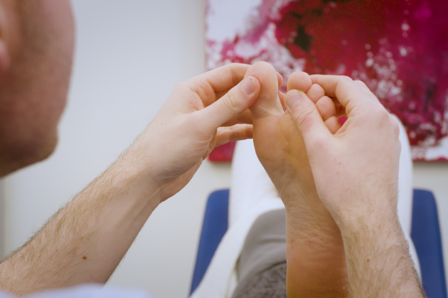 Image shows close up on patient foot as male nurse examines the toes
