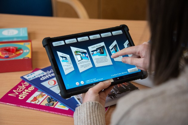 Person scrolling through tablet with books in the background