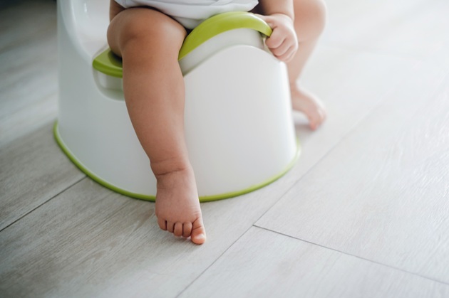 Small child's legs sitting on a white potty