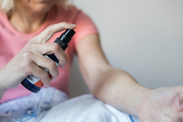Woman in pink top sraying HRT onto arm