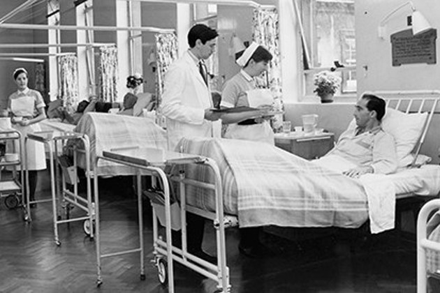 Nurses attend to patients in a hospital ward in the 1960s