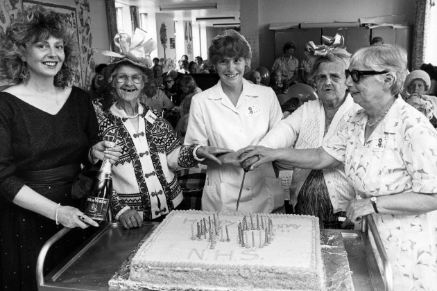 Nursing staff at North Tees General Hospital gather around a cake topped with candles spelling out '40' to celebrate the NHS's 40th anniversary in 1988