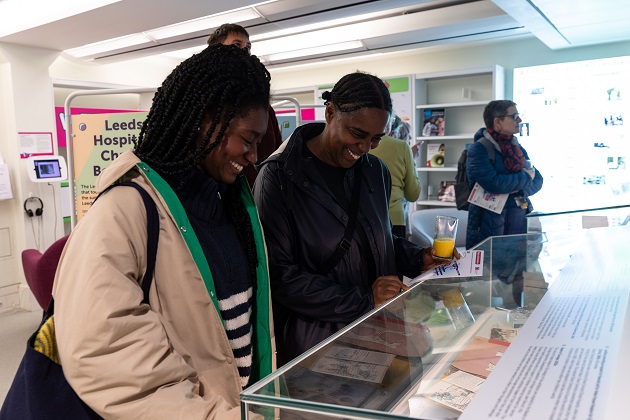 Two women smiling at exhibition display case