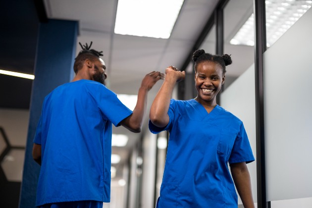 Two nursing staff smiling and giving high fives.